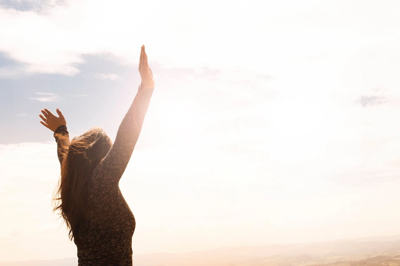 Person worshipping with raised hands representing present-hour manifestation